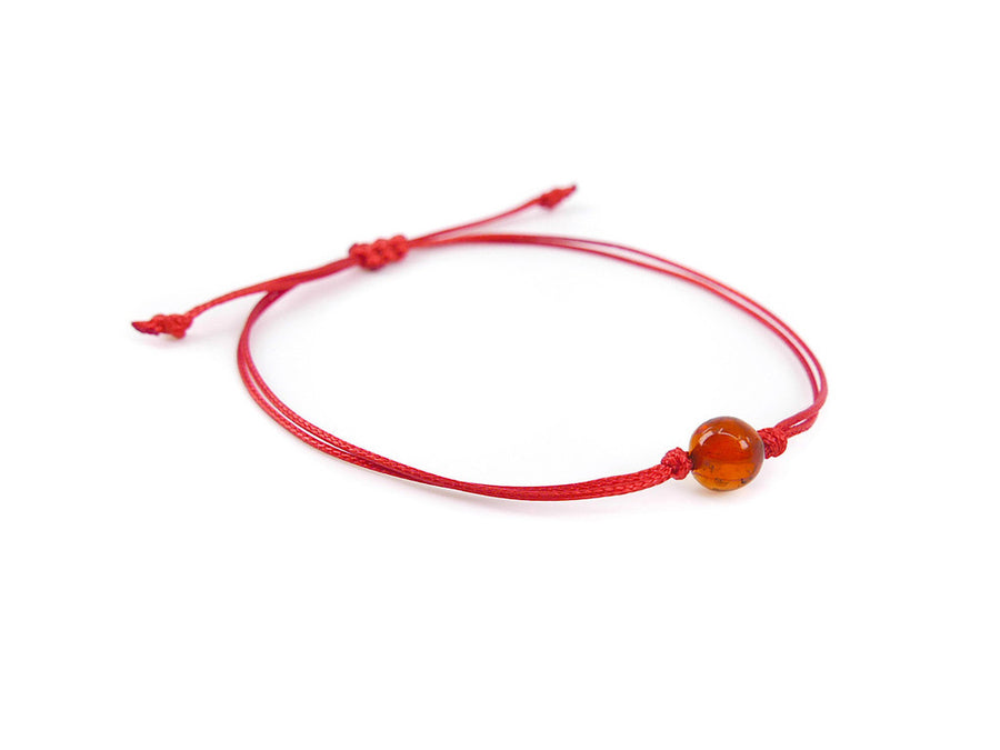 Pulsera artesanal de hilo rojo con ámbar báltico pulido color coñac, combinación de estilo y protección