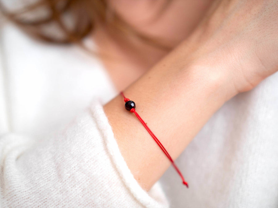 Pulsera ajustable de hilo rojo con ámbar báltico pulido color cereza oscura, ideal para energía y bienestar