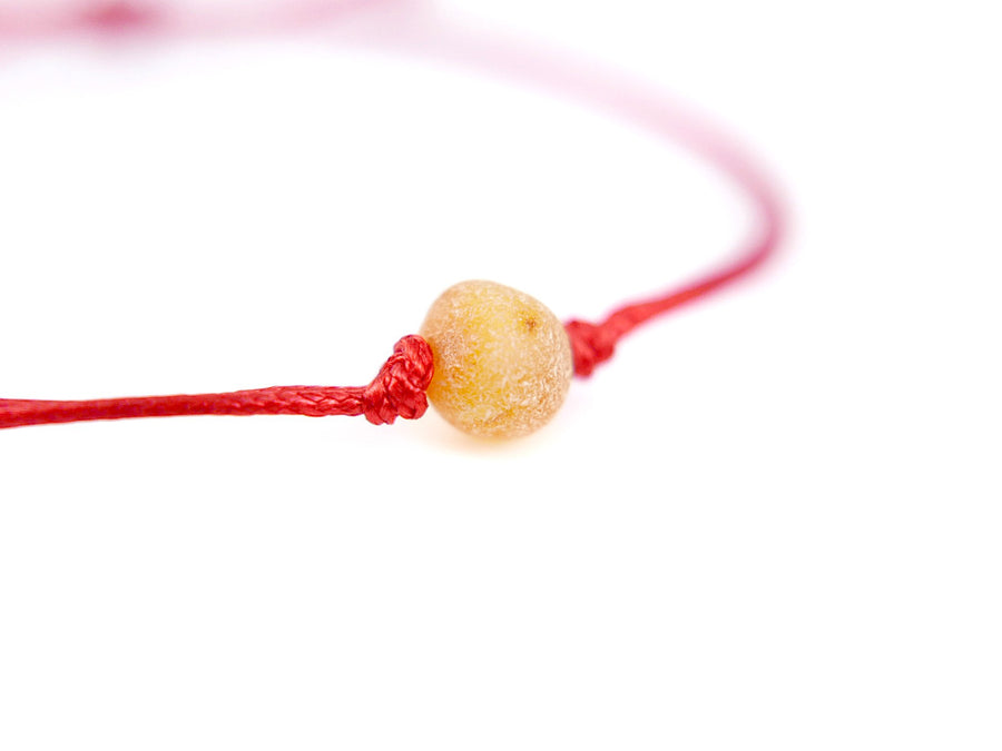 Pulsera de hilo rojo con ámbar natural sin pulir en color miel, protección y bienestar
