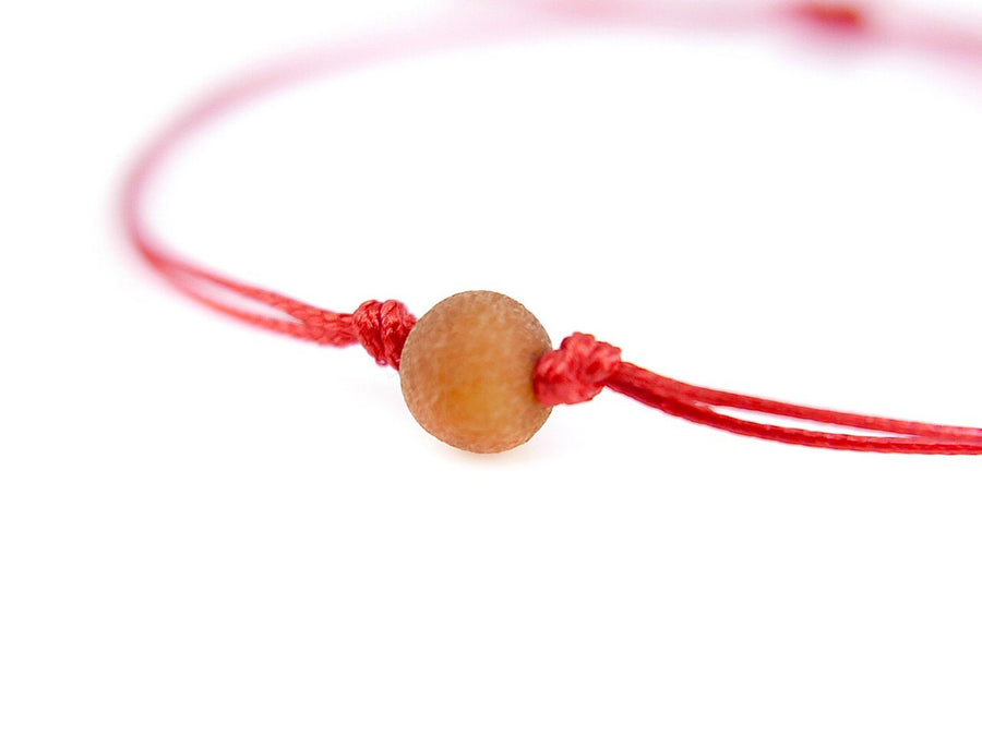 Pulsera protectora de hilo rojo con cuentas de ámbar báltico crudo color coñac