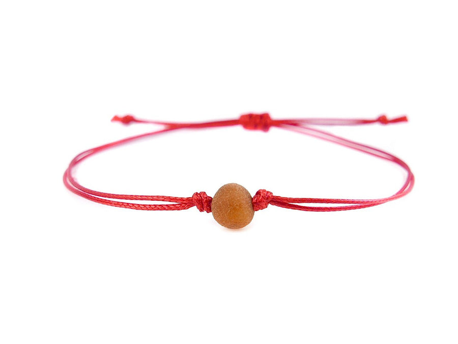 Ámbar báltico crudo color coñac en pulsera de hilo rojo, energía positiva y bienestar