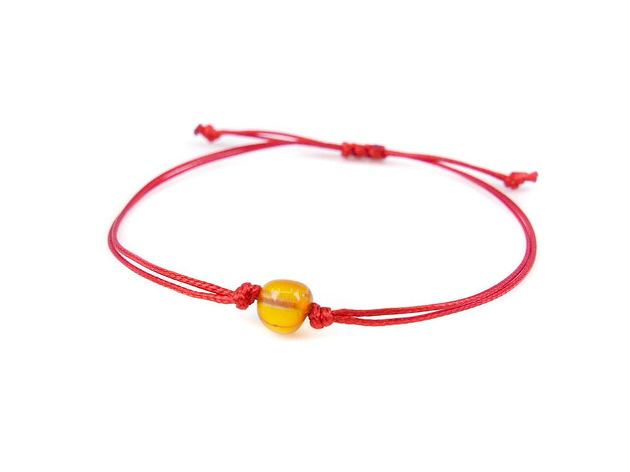 Pulsera de hilo rojo con ámbar báltico pulido en color miel, diseño elegante y protector
