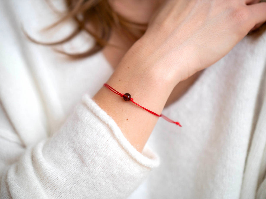 Pulsera ajustable de hilo rojo con ámbar báltico pulido color coñac, ideal para equilibrio y bienestar